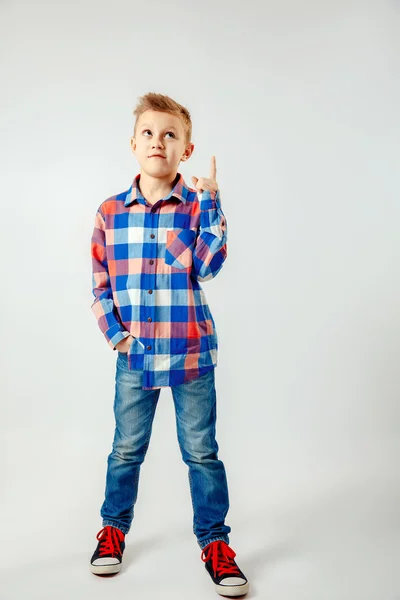 Jongen dragen van kleurrijke geruite shirt, blauwe jeans, gumshoes, naar boven geïsoleerd. copyspase. — Stockfoto