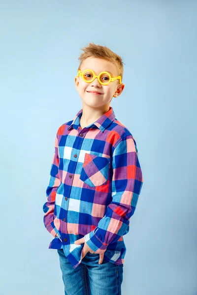 Niño vistiendo camisa a cuadros de colores, vaqueros azules, gafas de plástico que se divierten en el estudio — Foto de Stock