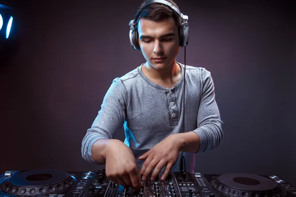 Junger Mann spielt Musik auf einem DJ-Mischpult im Studio — Stockfoto