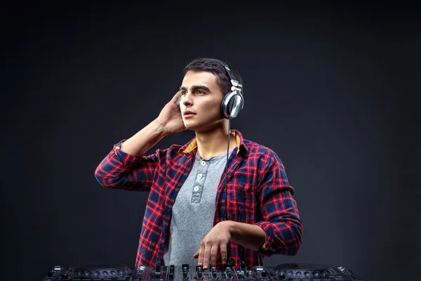 Un joven toca música en un mezclador de djs en el estudio —  Fotos de Stock