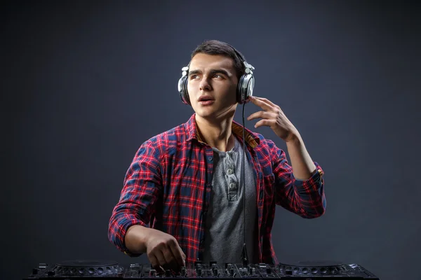 Un joven toca música en un mezclador de djs en el estudio —  Fotos de Stock