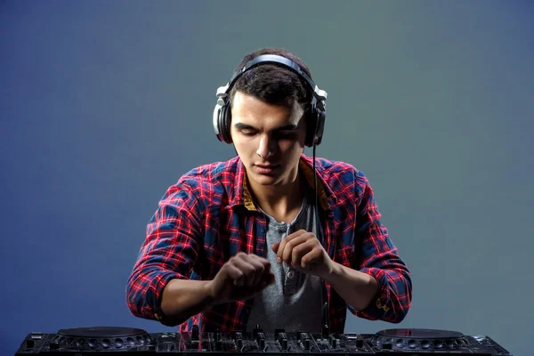 Un joven toca música en un mezclador de djs en el estudio —  Fotos de Stock