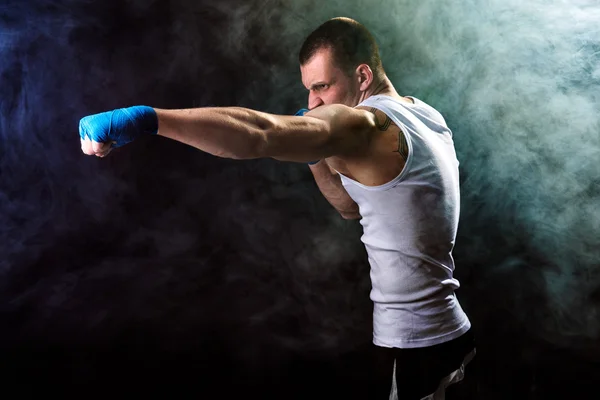 Muscular kickbox o muay thai luchador puñetazos en el humo — Foto de Stock