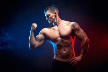 Yakışıklı güç atletik erkek vücut geliştiricisi. Fitness kas vücut koyu duman arka plan üzerinde. Mükemmel erkek. Harika vücut geliştirmeci, dövme, poz.