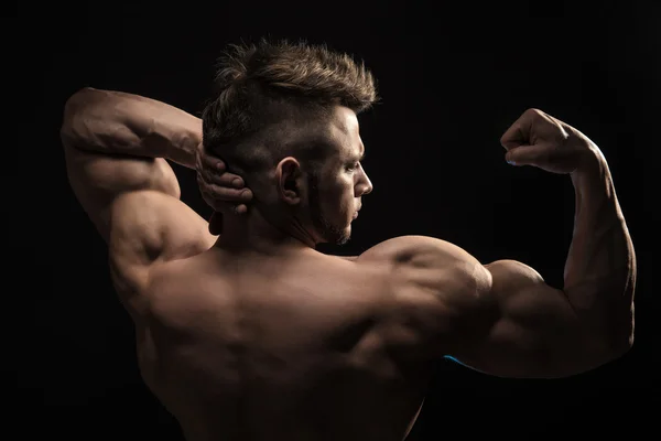 Strong Athletic Man Fitness Model posando músculos de la espalda, tríceps, latissimus sobre fondo negro — Foto de Stock