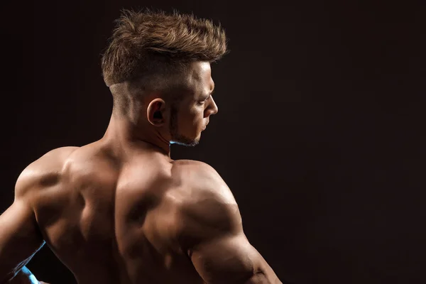 Atletik erkek fitness model siyah arka plan üzerinde sırt kasları, triceps, latissimus poz — Stok fotoğraf