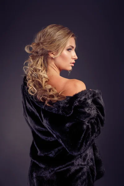 Moda seductora señora de pelo rubio en un abrigo de piel elegante y ropa interior negra sobre un fondo oscuro. Retoque . —  Fotos de Stock