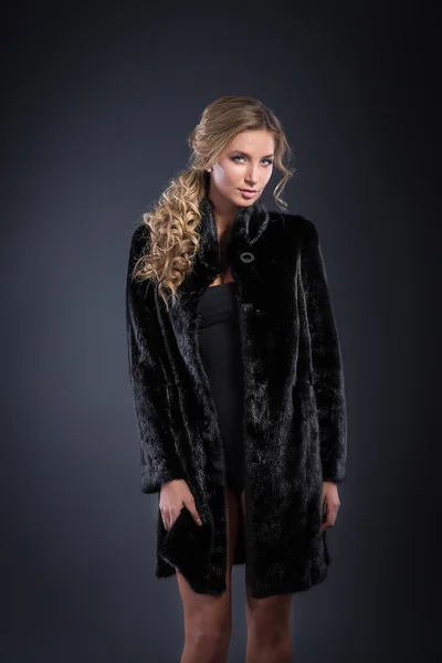 Fashion seductive blond hair lady in an elegant fur coat and black underwear on a dark background. Retouched. — Stock Photo, Image