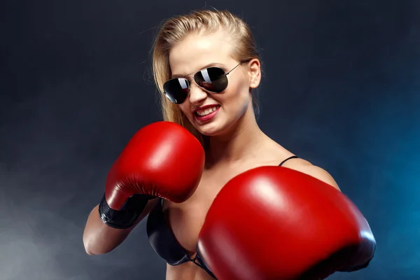 Bela menina boxer loira sexy vestida com luvas vermelhas, óculos de sol e lingerie preta. retrato de estúdio de jovem lutadora mulher . — Fotografia de Stock