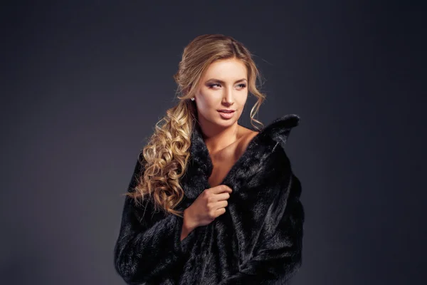 Moda seductora señora de pelo rubio en un abrigo de piel elegante y ropa interior negra sobre un fondo oscuro. Retoque . —  Fotos de Stock
