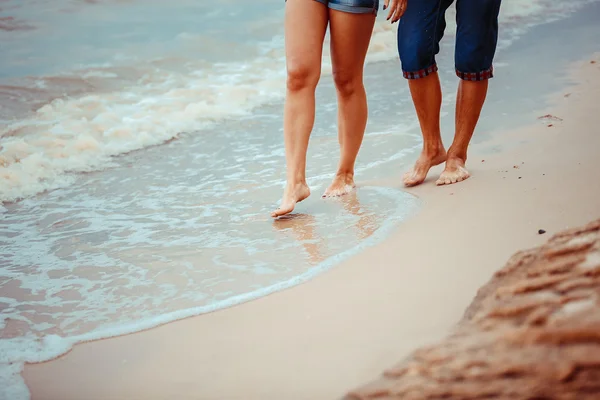 Pés de casal. Mulher e homem nas ondas do mar ao pôr do sol — Fotografia de Stock