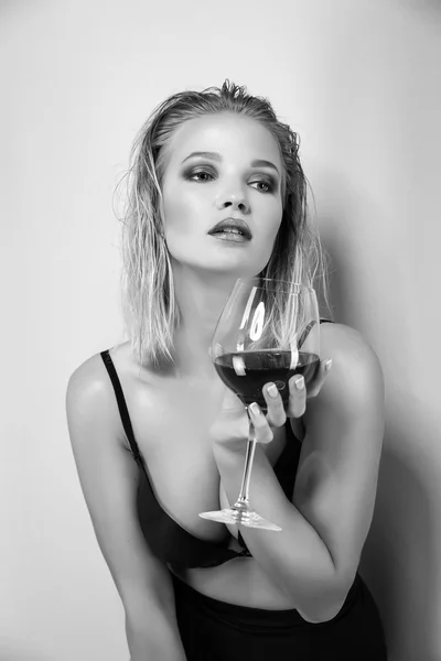 Blonde woman holding glass of wine. Beautiful female model. Hot lady in black lingerie. Fashion studio shot. Slim girl. After party. Black and wihte. — Stock Photo, Image