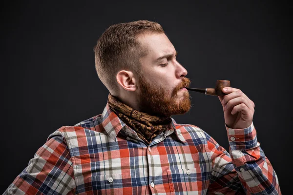 Retrato de homem barbudo cachimbo de fumar com olho espremido — Fotografia de Stock