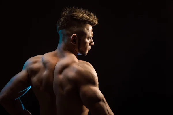 Ισχυρή Αθλητικό γυμναστήριο άνθρωπος που θέτουν τους ραχιαίους μυς, τρικέφαλος μύς, Πλατύ πάνω από το μαύρο φόντο — Φωτογραφία Αρχείου