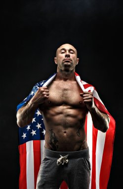 Handsome bald topless man with American flag on shoulders
