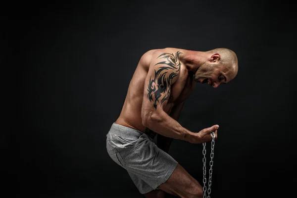 Homem careca forte tentando rasgar a corrente de metal — Fotografia de Stock