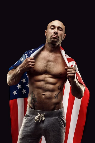 Bonito homem careca topless com bandeira americana nos ombros — Fotografia de Stock