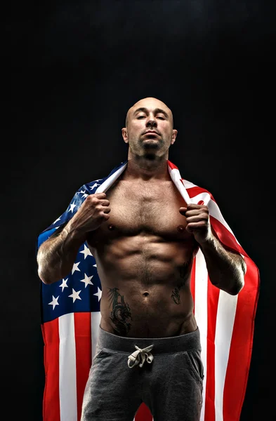 Bonito homem careca topless com bandeira americana nos ombros — Fotografia de Stock