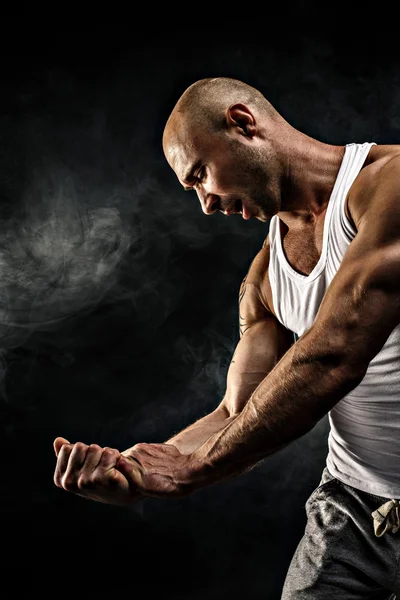 Hombre en camiseta blanca con músculos fuertes en el fondo negro — Foto de Stock