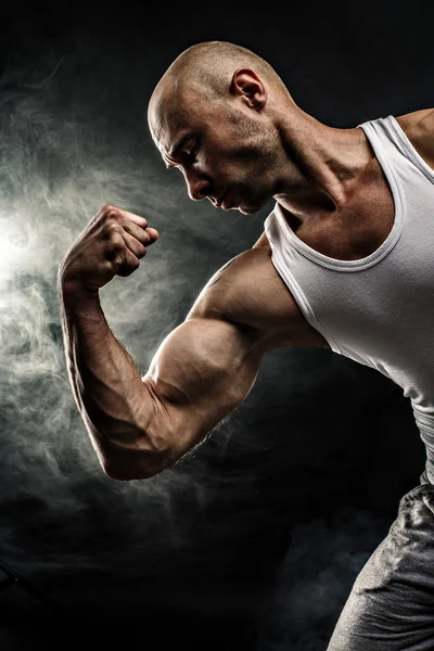 Hombre en camiseta blanca con músculos fuertes en el fondo negro — Foto de Stock