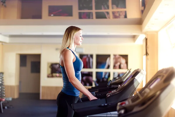 Mujer joven en el gimnasio haciendo ejercicio. Ejecutar en una máquina . —  Fotos de Stock