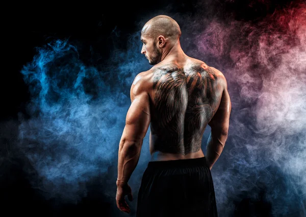 Вид сзади на позу татуированного мускулистого человека. Взгляд в сторону — стоковое фото