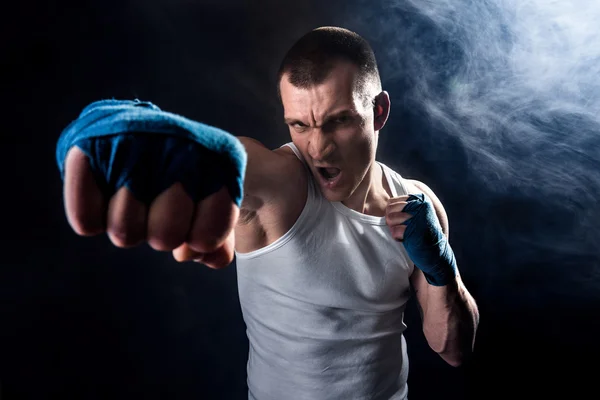 Muscular kickbox or muay thai fighter punching in smoke. — Stock Photo, Image