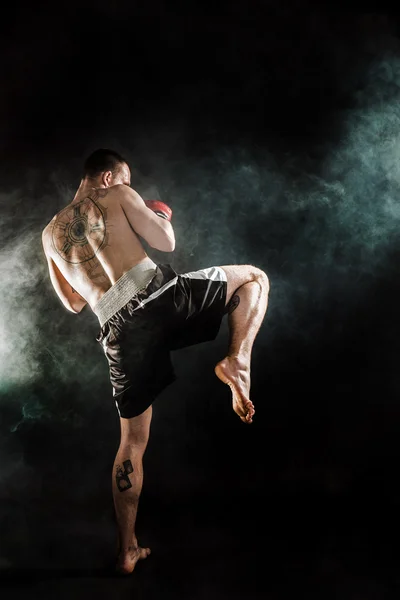 Svalnatý kickbox nebo muay thai bojovník děrování v kouři. — Stock fotografie