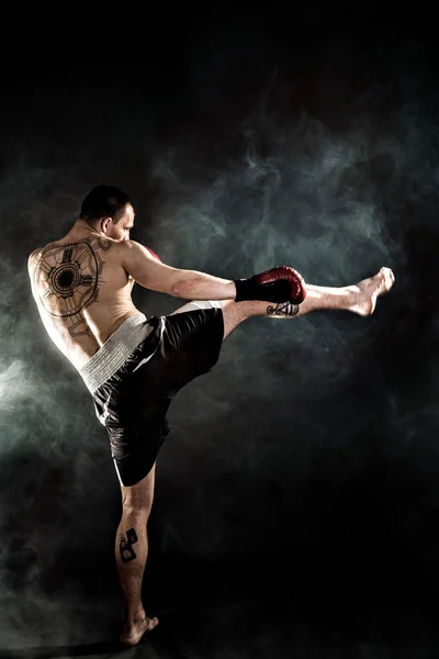 Muscular kickbox o muay thai luchador puñetazos en el humo . — Foto de Stock