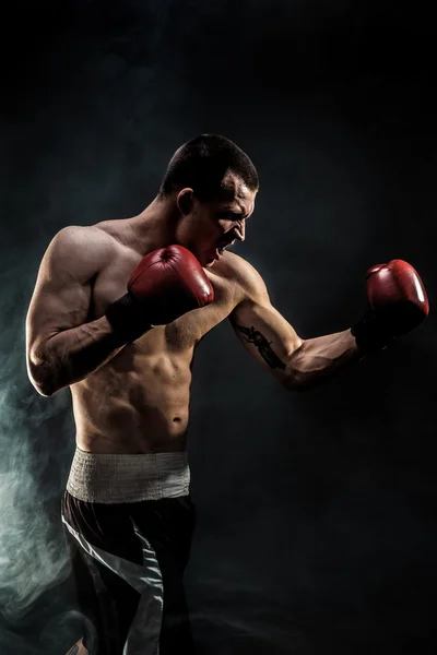 Muscular kickbox ou muay thai lutador perfurando na fumaça . — Fotografia de Stock