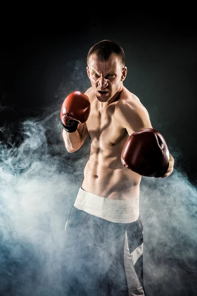 Muscular kickbox o muay thai luchador puñetazos en el humo . — Foto de Stock