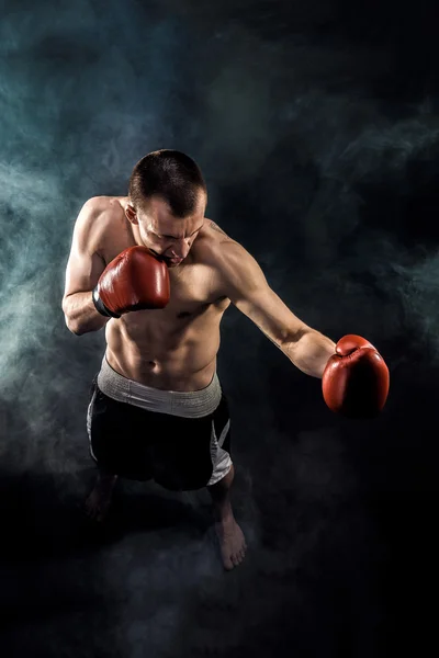 Muscular kickbox or muay thai fighter punching in smoke. — Stock Photo, Image