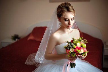 Kokulu bir yatağa oturmuş güzel gelin.