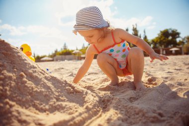 Kumsalda oynarken küçük kız.