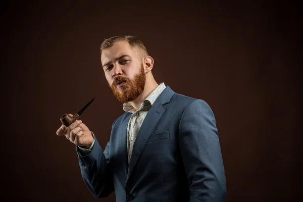 Elegante hombre con barba sosteniendo pipa humeante — Foto de Stock