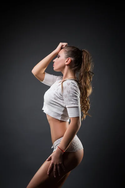 Side view of sexy girl in white against black background — Stock Photo, Image