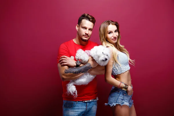 Pareja con perro blanco contra fondo brillante —  Fotos de Stock