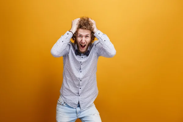 Depressief hysterische jonge man schreeuwen tegen van gele achtergrond — Stockfoto