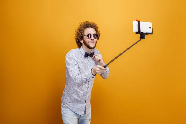 Curly-haired mens in zonnebrillen en ' bow-tie nemen selfie monopod gebruiken — Stockfoto