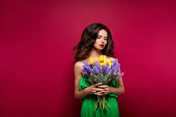 Bruna seducente dai capelli lunghi con bouquet di fiori. Sfondo vinoso. Isolato — Foto Stock