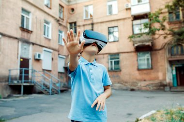 Fascinated little boy using VR virtual reality goggles. outdoor clipart