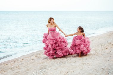Anne ve küçük kızı sahilde pembe elbiseli
