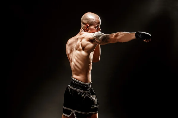 Muscular kickbox ou muay thai lutador perfurando na escuridão — Fotografia de Stock