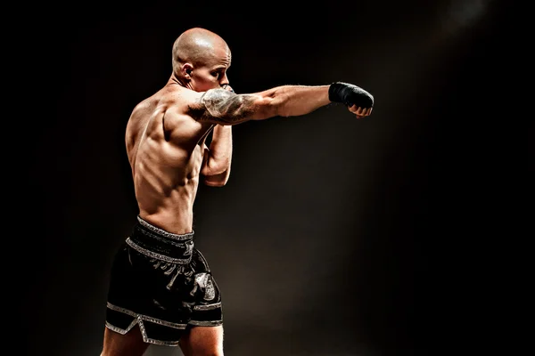 Muscular kickbox ou muay thai lutador perfurando na escuridão — Fotografia de Stock