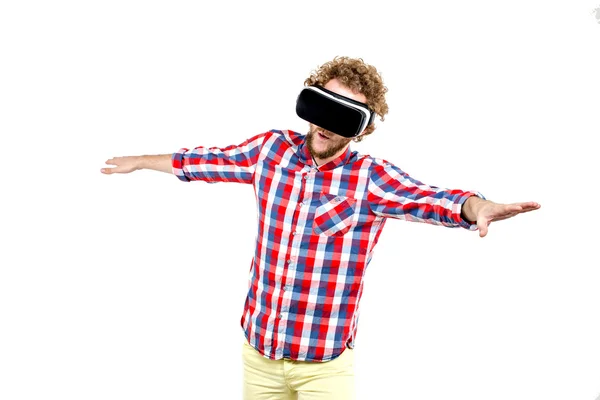 Молодий кучерявий чоловік у плетеній сорочці використовує гарнітуру VR і відчуває віртуальну реальність ізольовано на білому тлі — стокове фото