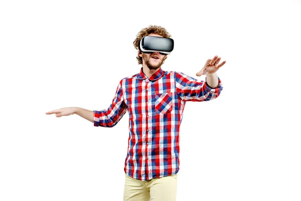 Молодий кучерявий чоловік у плетеній сорочці використовує гарнітуру VR і відчуває віртуальну реальність ізольовано на білому тлі — стокове фото