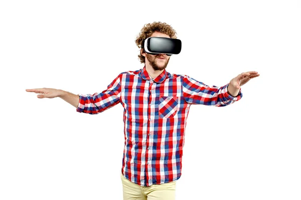 Joven hombre de pelo rizado con camisa a cuadros usando un auricular VR y experimentando realidad virtual aislado sobre fondo blanco —  Fotos de Stock
