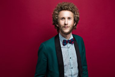 Şık adam papyon, yeşil bir ceket giyiyor kıvırcık saçlı sakallı. Kırmızı arka plan. İzole