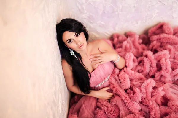 La hermosa morena con maquillaje tierno posando en un vestido de novia rosa . — Foto de Stock