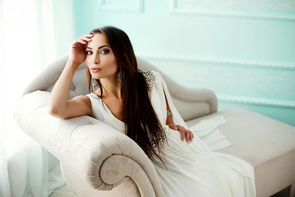 Mujer sensual en vestido blanco en sofá — Foto de Stock